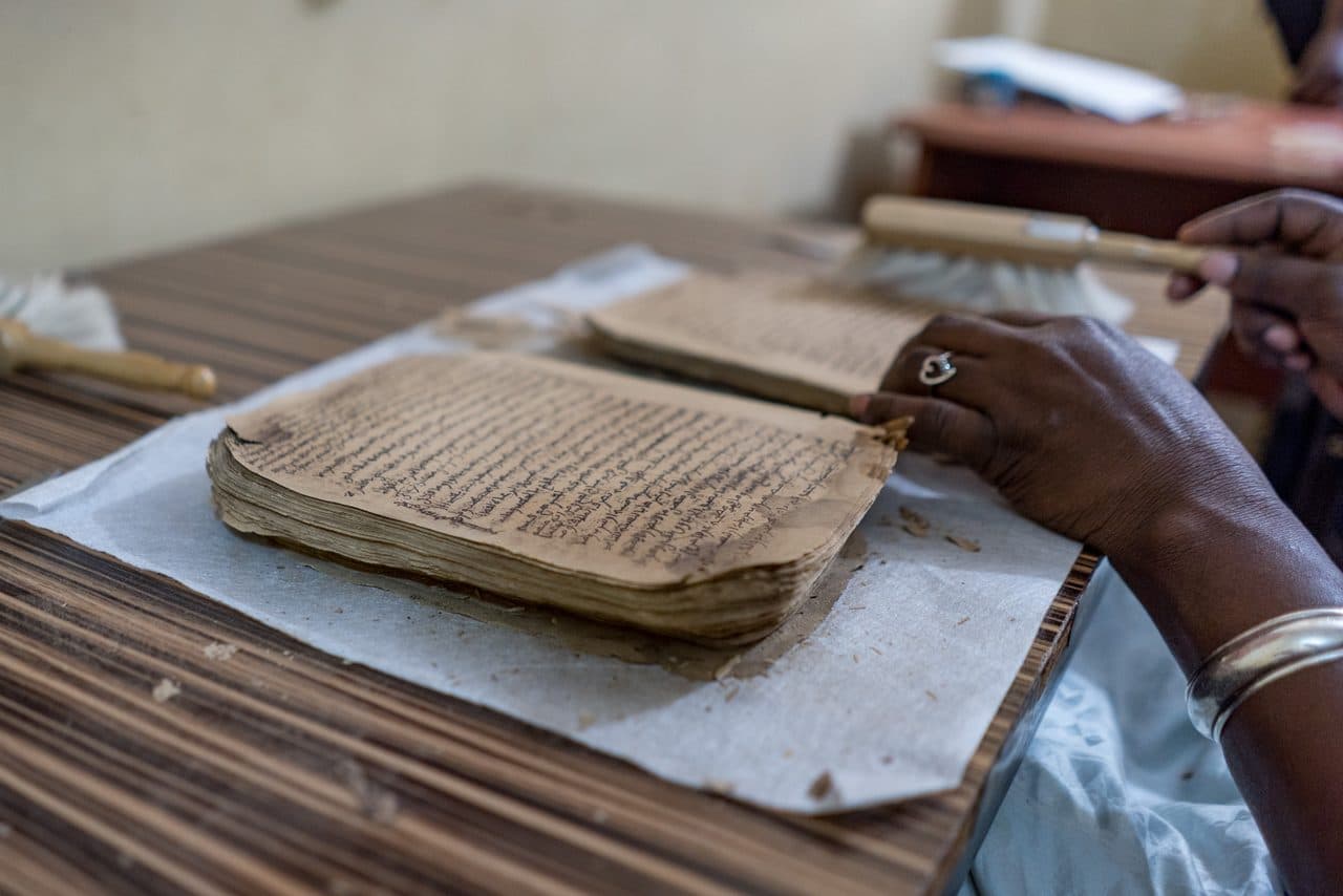Mains examinant des manuscrits anciens de Tombouctou